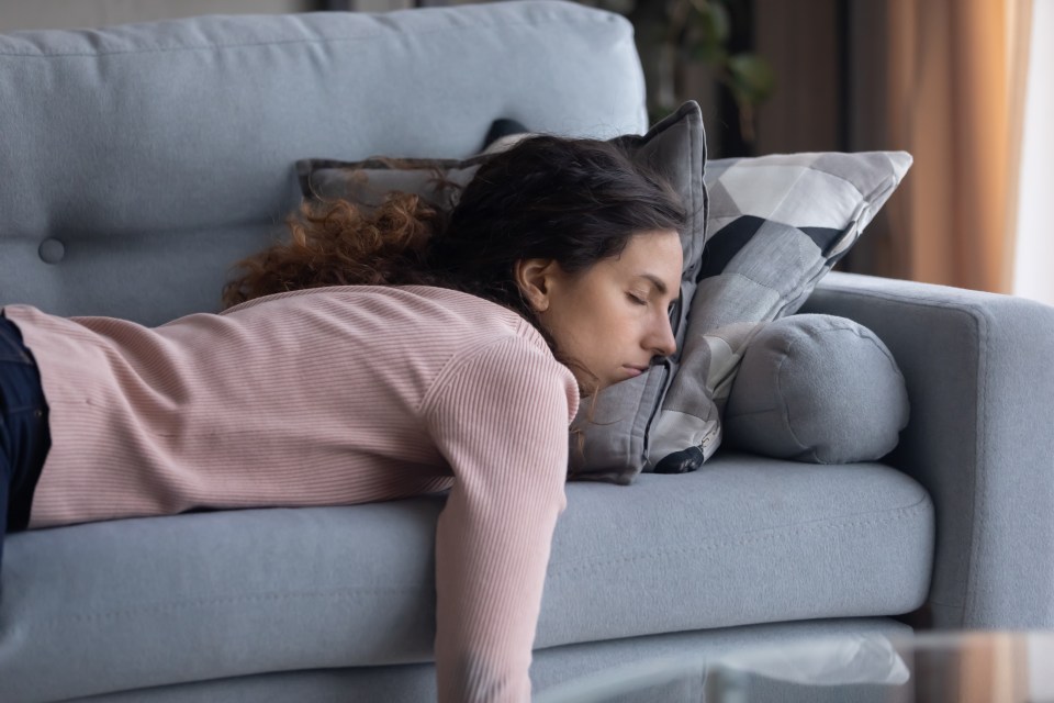 a woman laying on a couch with her head on a pillow