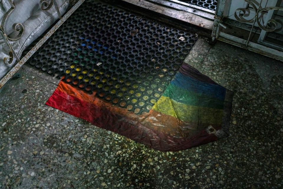 LGBTQ+ flag is seen under a rubber door mat at an entrance to a basement of the office building