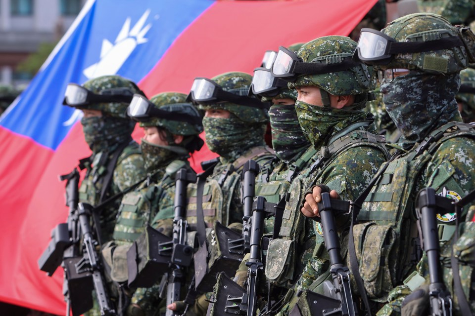 Soldiers pose for group photos with a Taiwan flag in war games to simulate a Chinese invasion