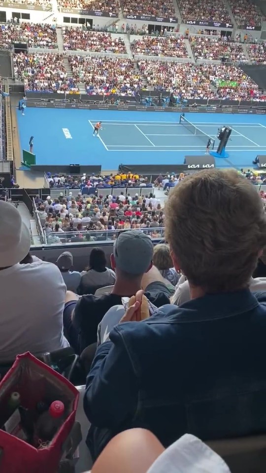 A tennis fan clutched a hotdog while watching the Australian Open