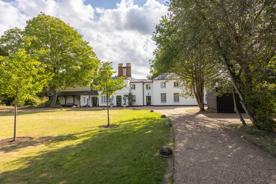 a large white house is surrounded by trees and a gravel driveway