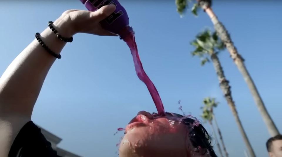 A fan pours Purple-Grape flavoured Prime over his eyes and hair