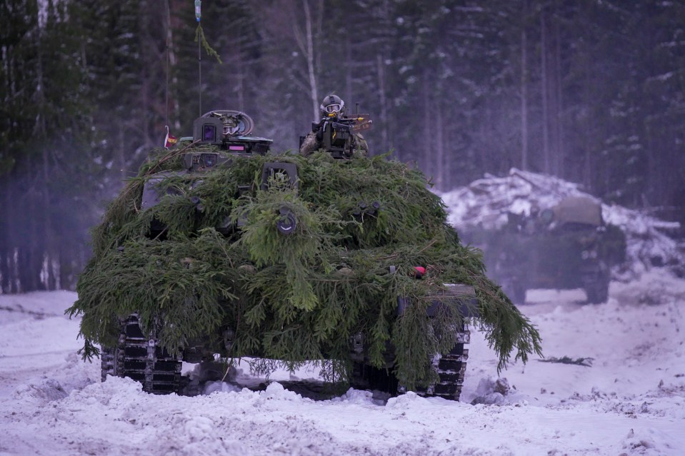 Tanks covered in camouflage roll through the snow