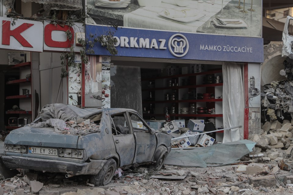 A shop and a car lie in ruins in Hatay