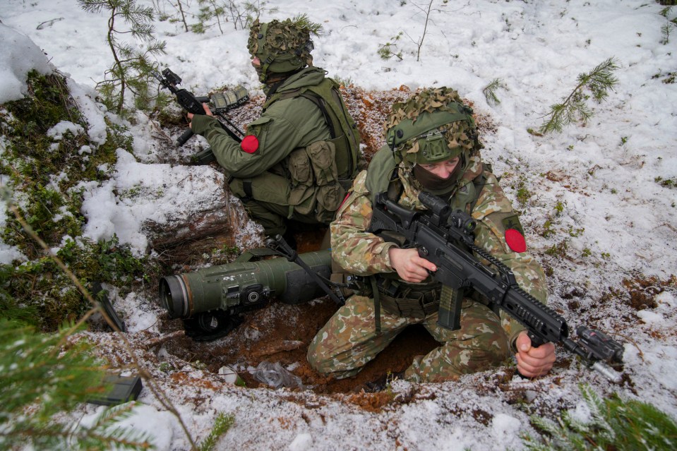 Two soldiers hunker down a foxhole with a rocket launcher