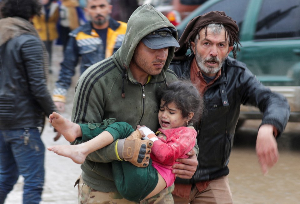 A man carries a little girl to safety after the devastating earthquake in Turkey and Syria