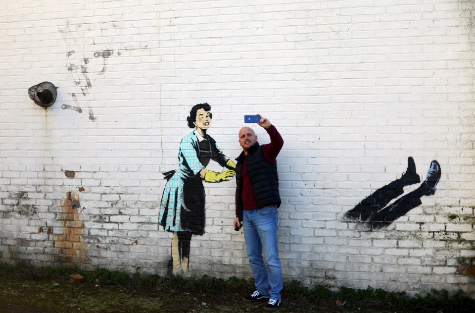 A baffled local poses in front of the ruined mural