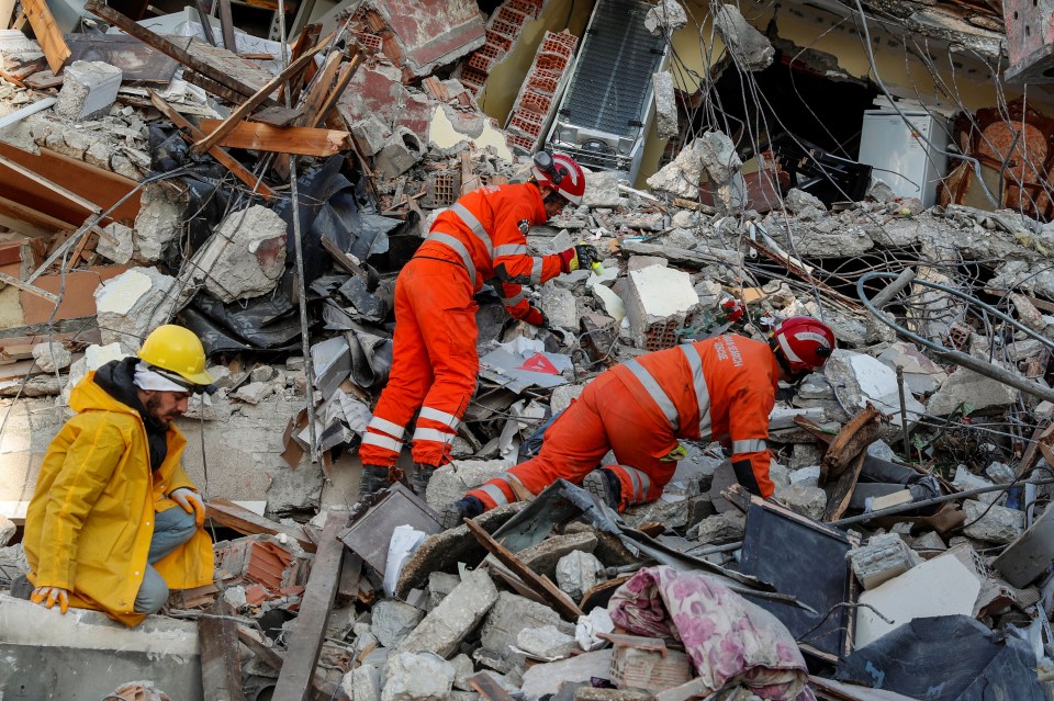 Members of a search and rescue team work on the site of a collapsed building, as the search for survivors continues