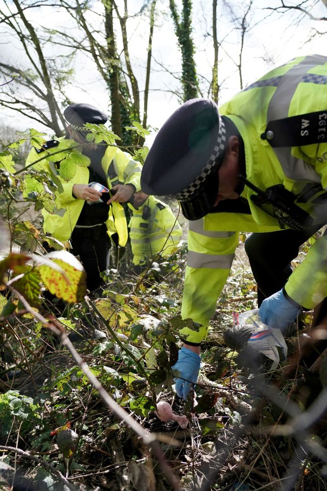 An officer recovers what appear to be a pair of pink child's ear muffs from the ground