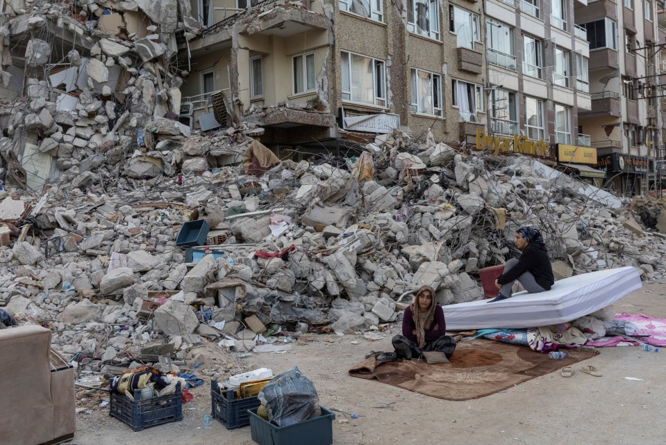 Perihan Fansa and Ayfer Sarac sit outside a destroyed building