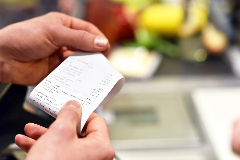 Hands holding a supermarket receipt showing a total of 37.11 EUR.