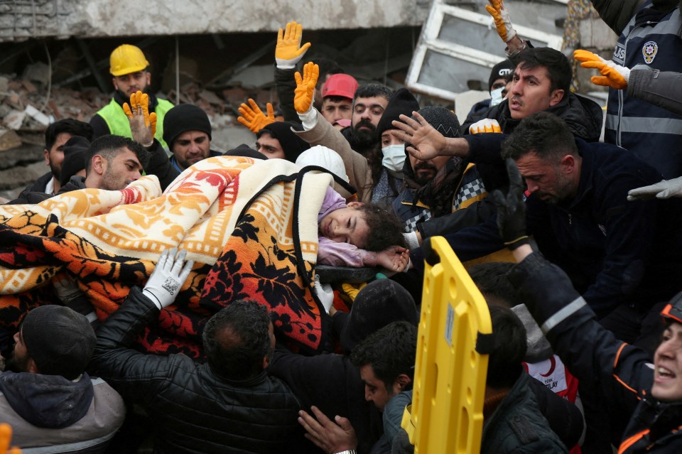 Rescuers carry a girl out from a collapsed building after a 7.8 magnitude earthquake in Turkey