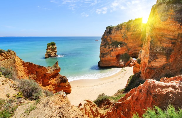 the sun shines brightly on a beach surrounded by rocks