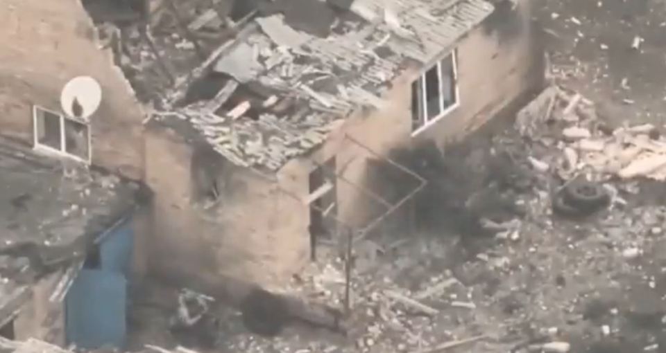 A soldier standing next to a burnt out house