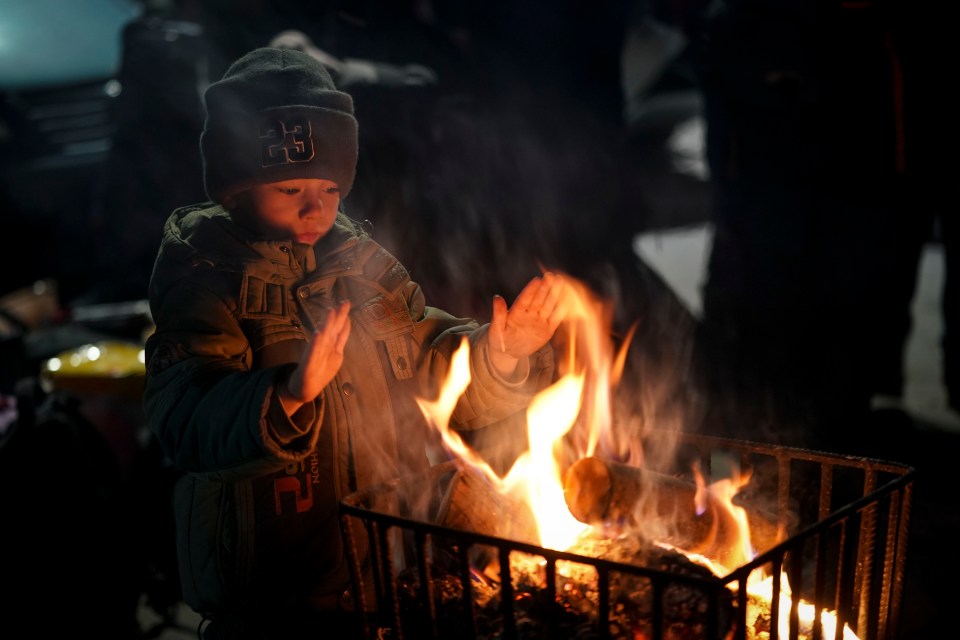 Three-year-old Ukrainian boy, Daniel Mikrukov, warms his hands on a fire in a refugee camp on the Polish border on March 7, 2022