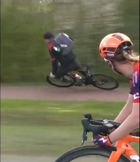 A cyclist lost their balance and fell over as professional riders approached