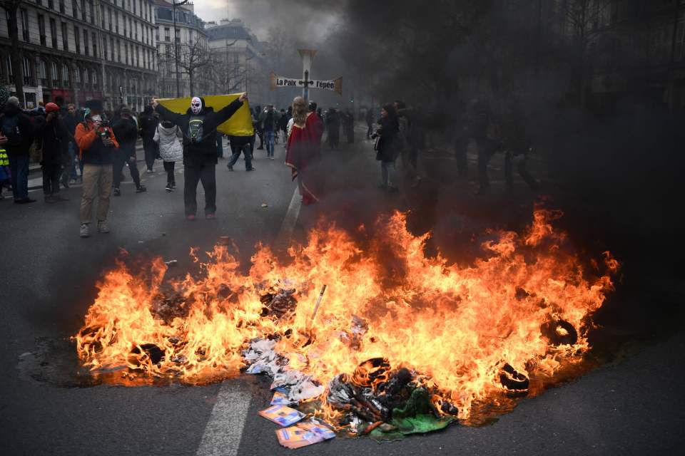 A fire burns during a demonstration in Paris as thousands take to the streets in France