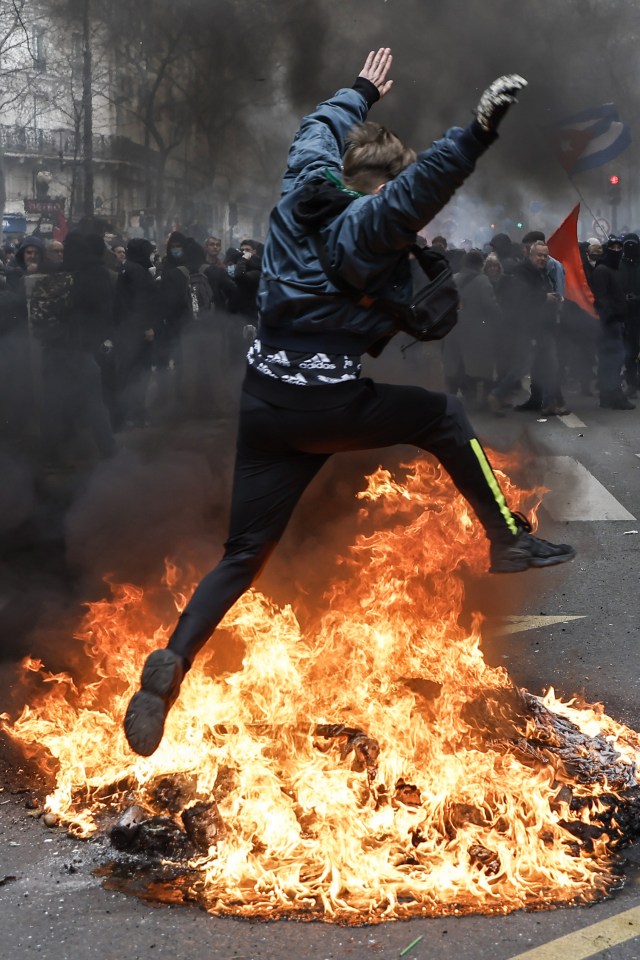 A protester jumps over a blaze in the streets of Paris