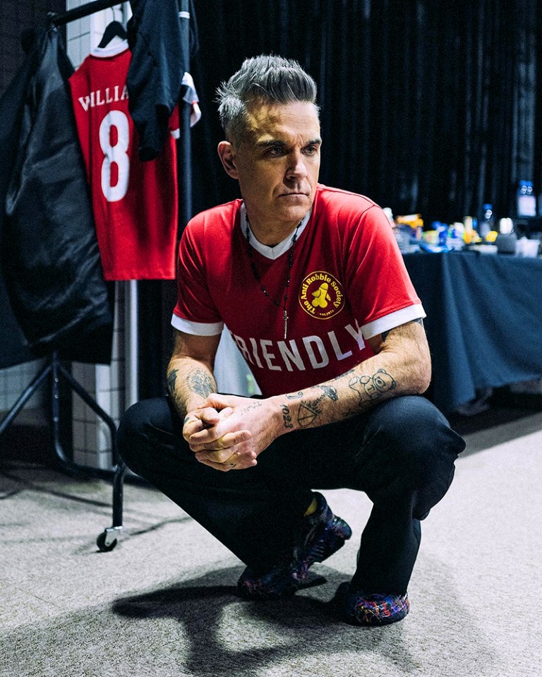 Robbie Williams wore this personalised football shirt which features an emblem that reads: 'The Anti ­Robbie Society'