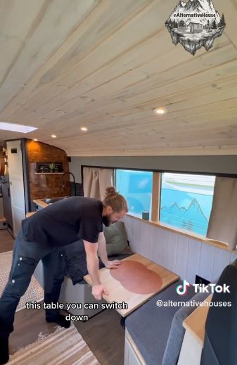 The guy shows how the table can be pushed down to convert the dining area into a bed