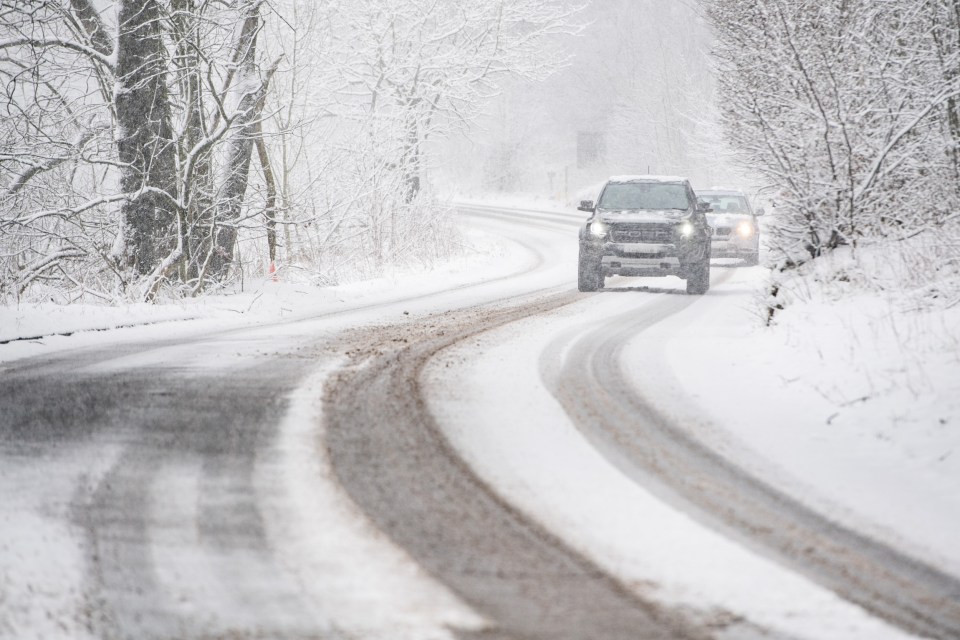 Vehicles make their way through heavy snow at Rushop Edge in the Peak District near Chapel en le Frith in Derbyshire