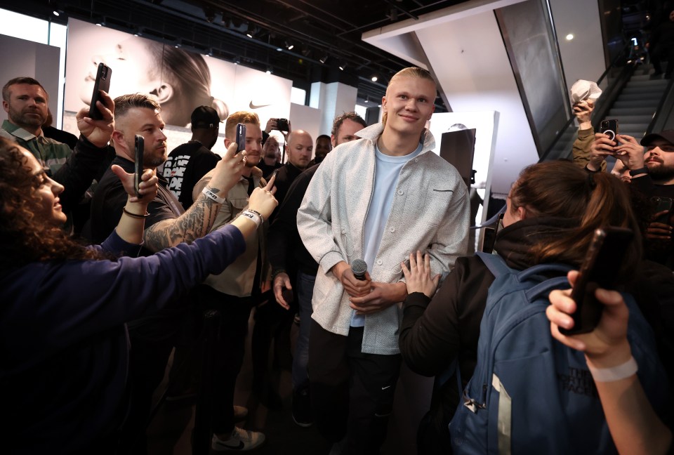 a group of people are taking pictures of a man in a nike shirt