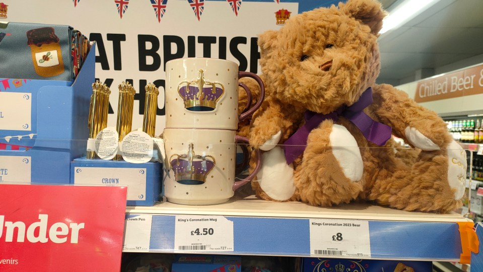 A royal teddy bear, mugs and pens for sale in a supermarket