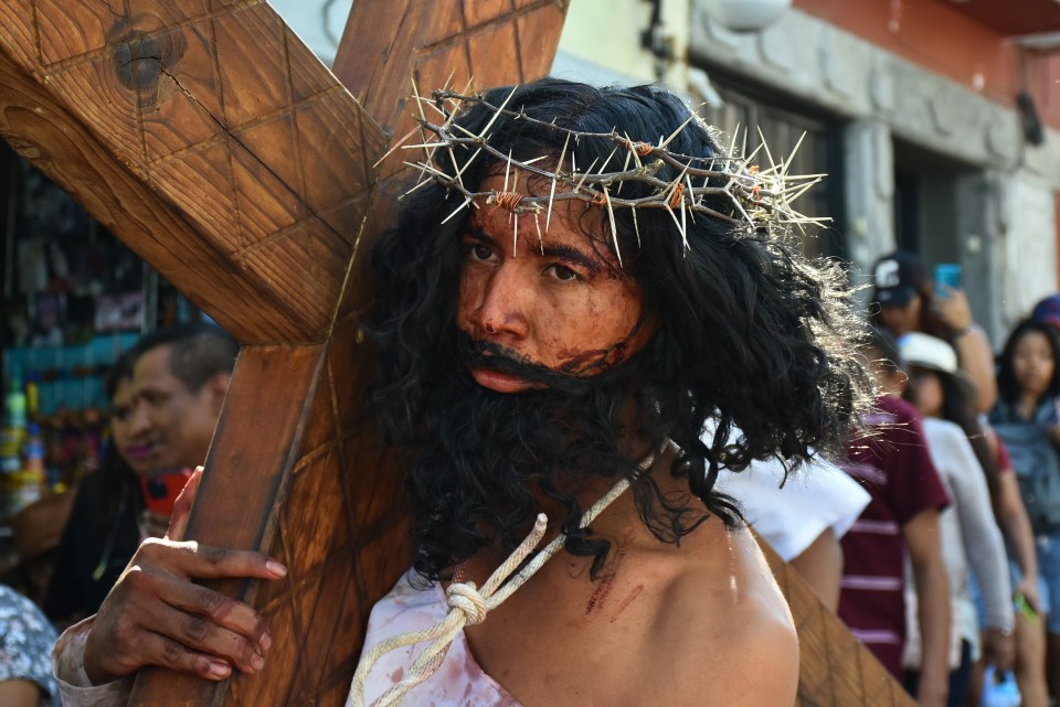 An actor portraying Jesus carries the cross into the town centre