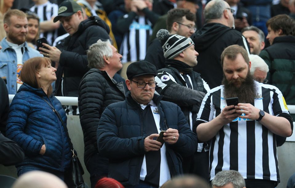 Newcastle fans check their phones during the match with Tottenham