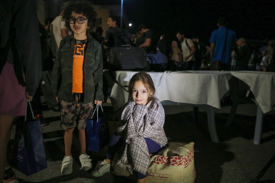 Children evacuated from Sudan wait after arriving at a military airport in Amman