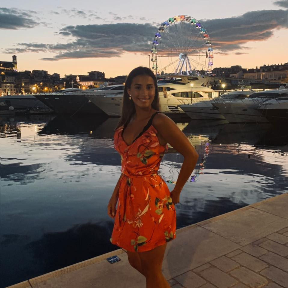 a woman in an orange dress stands in front of a ferris wheel