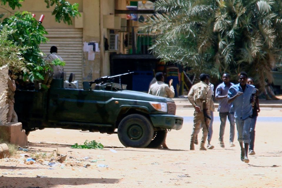 People run past a military vehicle in the capital as clashes in the city continue