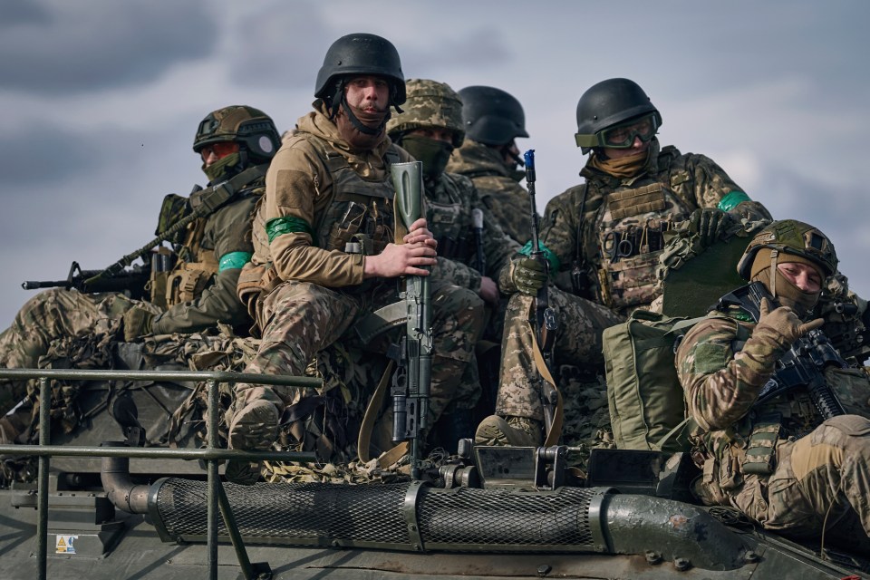 Ukrainian soldiers ride atop an APC on the frontline in Bakhmut