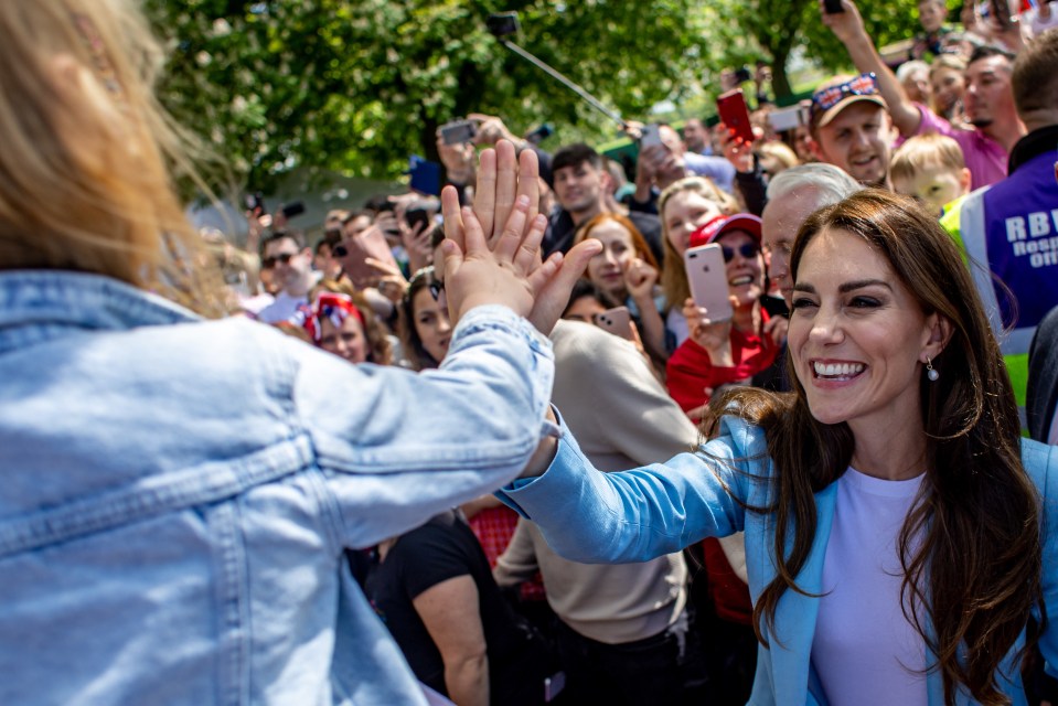 Kate beamed as she high-fived a fan on the Long Walk