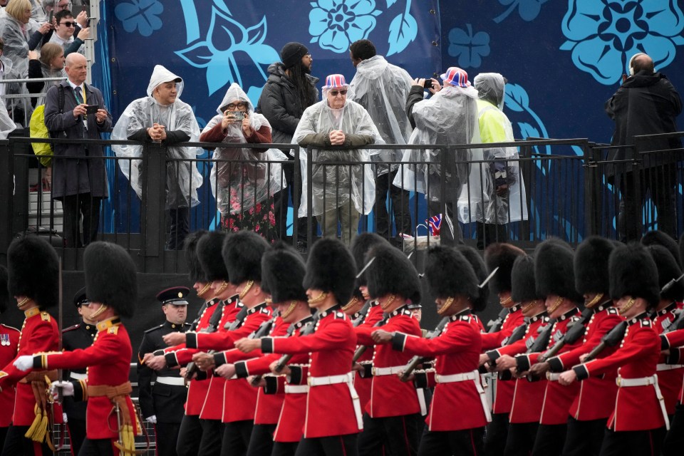 Royal fans try to keep themselves dry as the Coldstream Guards march past as part of coronation celebrations