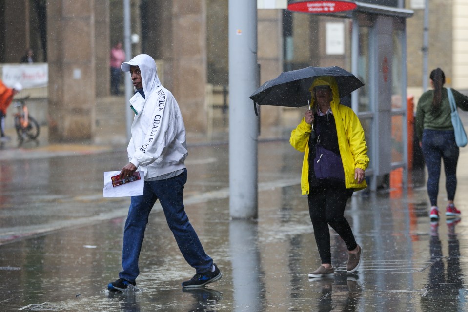 Pedestrians get caught in a heavy rainfall outside London Bridge station