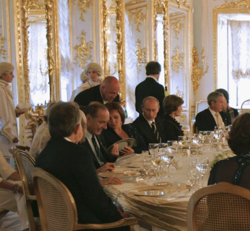 Prigozhin leans in behind Putin as he serves at the G8 in 2006