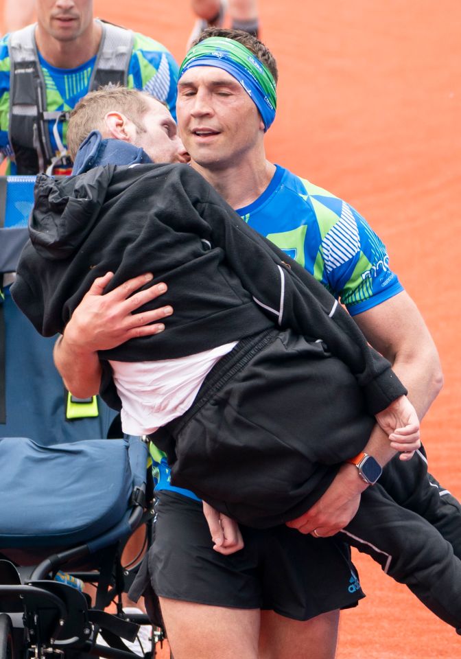 Former rugby league player Rob Burrow, cruelly struck down by motor neurone disease, being carried over the marathon finish line by his ex-team-mate, Kevin Sinfield