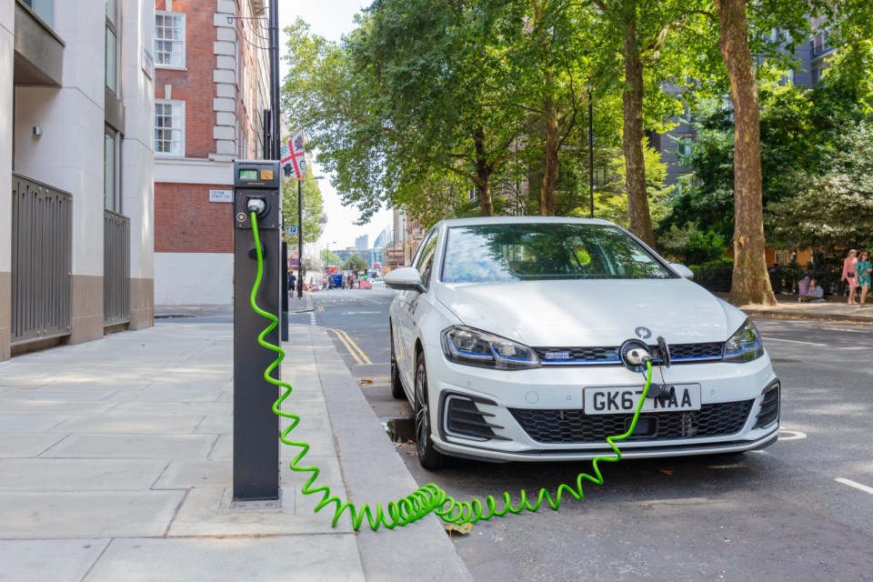 PBX7RJ London, England, UK; 27th July 2018; White Volkswagen Golf GTE Plug-In Hybrid Electric Car Charging in a Central London Street