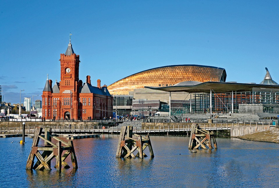 View of Cardiff city skyline from across the bay showing the Pier head building National Assembly for Wales and the millennium centre against a blue sky.