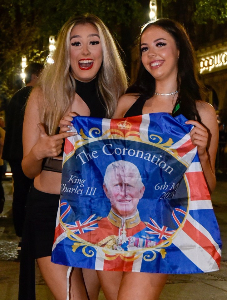 Two pals out celebrating in Newcastle display a Union flag with Charles' face on it