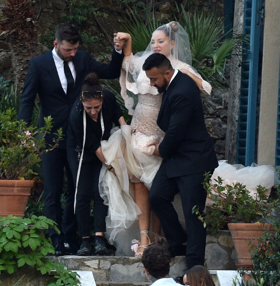 The star is helped down the steps in her beautiful gown