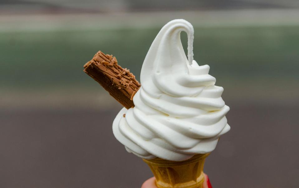 a person is holding an ice cream cone with a piece of chocolate on top