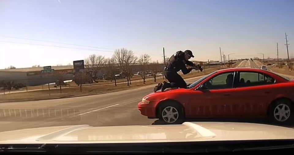 The police officer clung onto the hood of the car as the suspect drove away