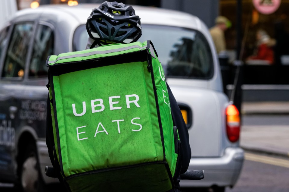 a person wearing a helmet and carrying an uber eats bag