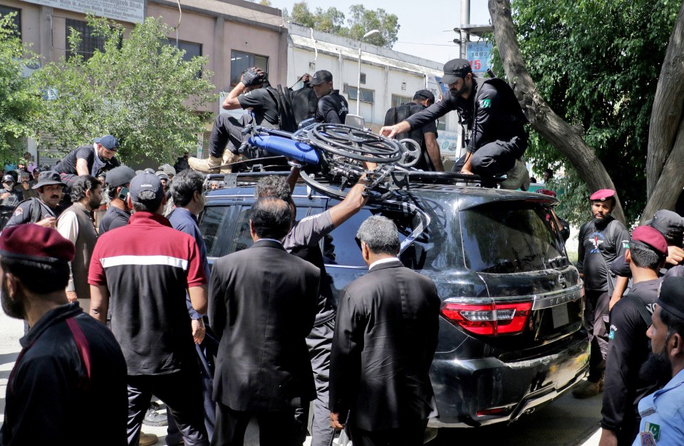 Security officials lifting Khan's wheelchair