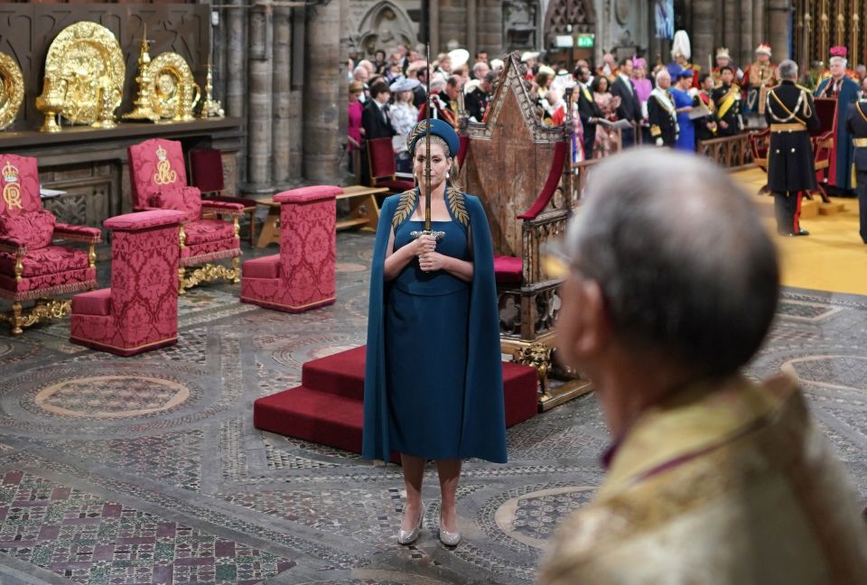 Wearing a teal dress and cape embroidered with gold ferns, Penny Mordaunt clutched the heavy sword