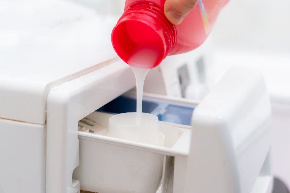 pouring the washing conditioner in the washing machine to get clean clothes