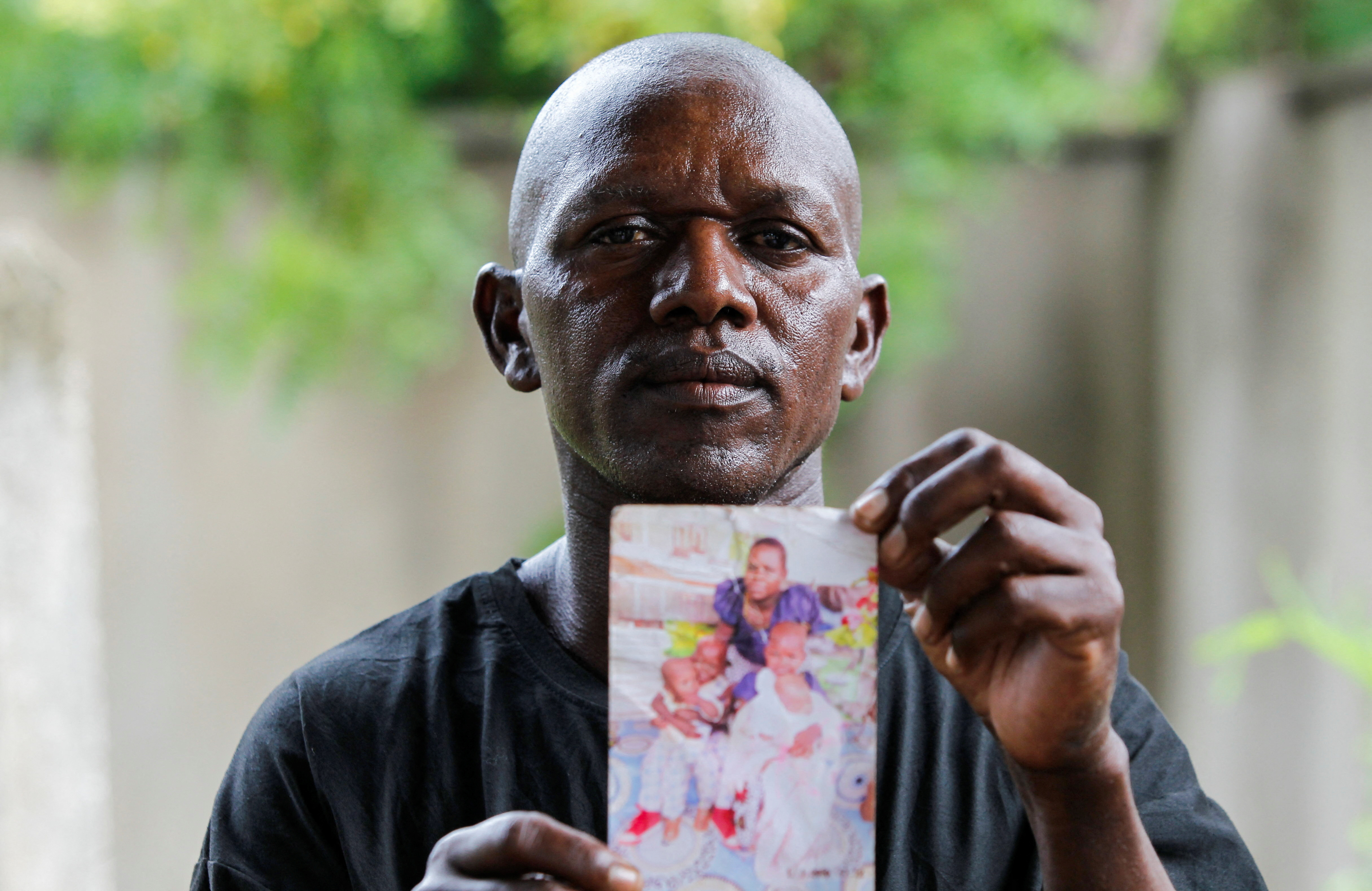 Former cult member Steven Mwiti holding a picture of his wife and children