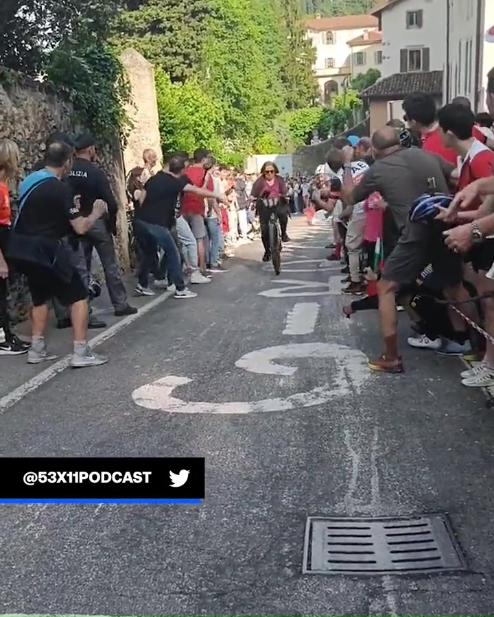 The crowd suddenly parts as a cyclist emerges - but it's not who they were expecting